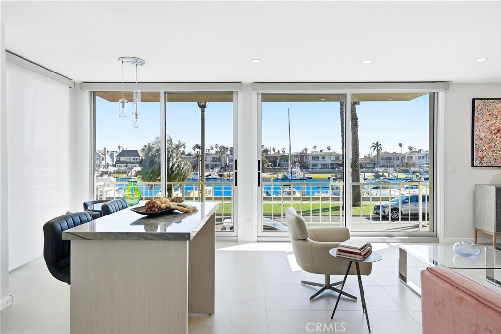 Open-plan kitchen and living area with a marble island and marina views through sliding glass doors.