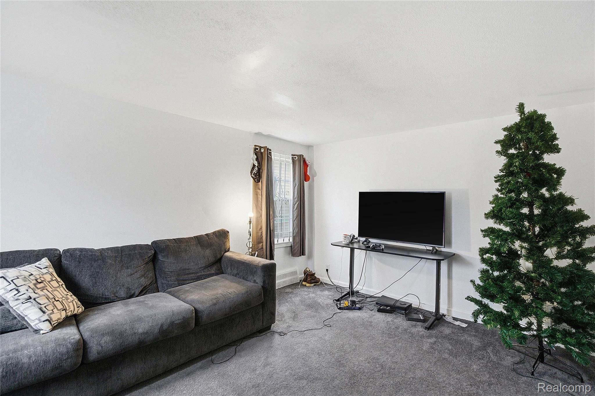 Living room with a gray sectional sofa, television, and artificial Christmas tree.