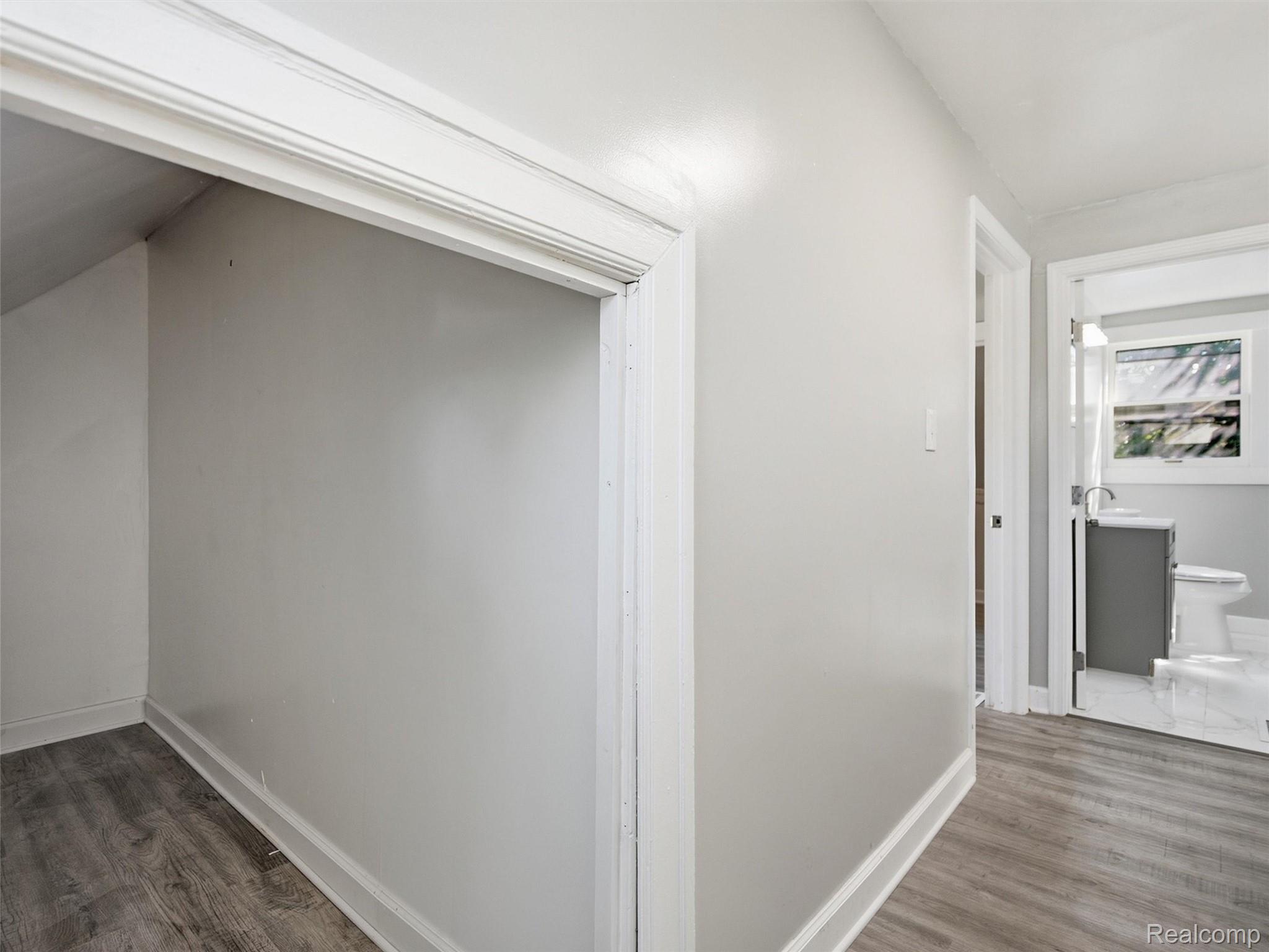 Hallway with an under-stair alcove and a bathroom visible through the doorway.