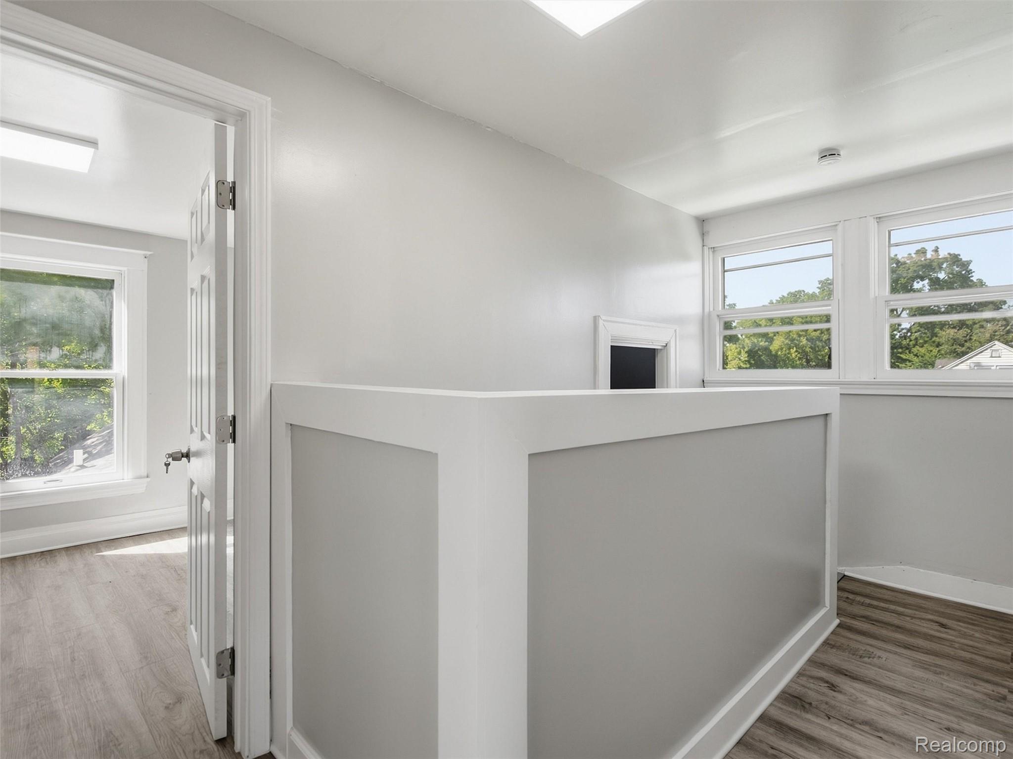 Upper-level landing with a white half-wall railing and large windows.