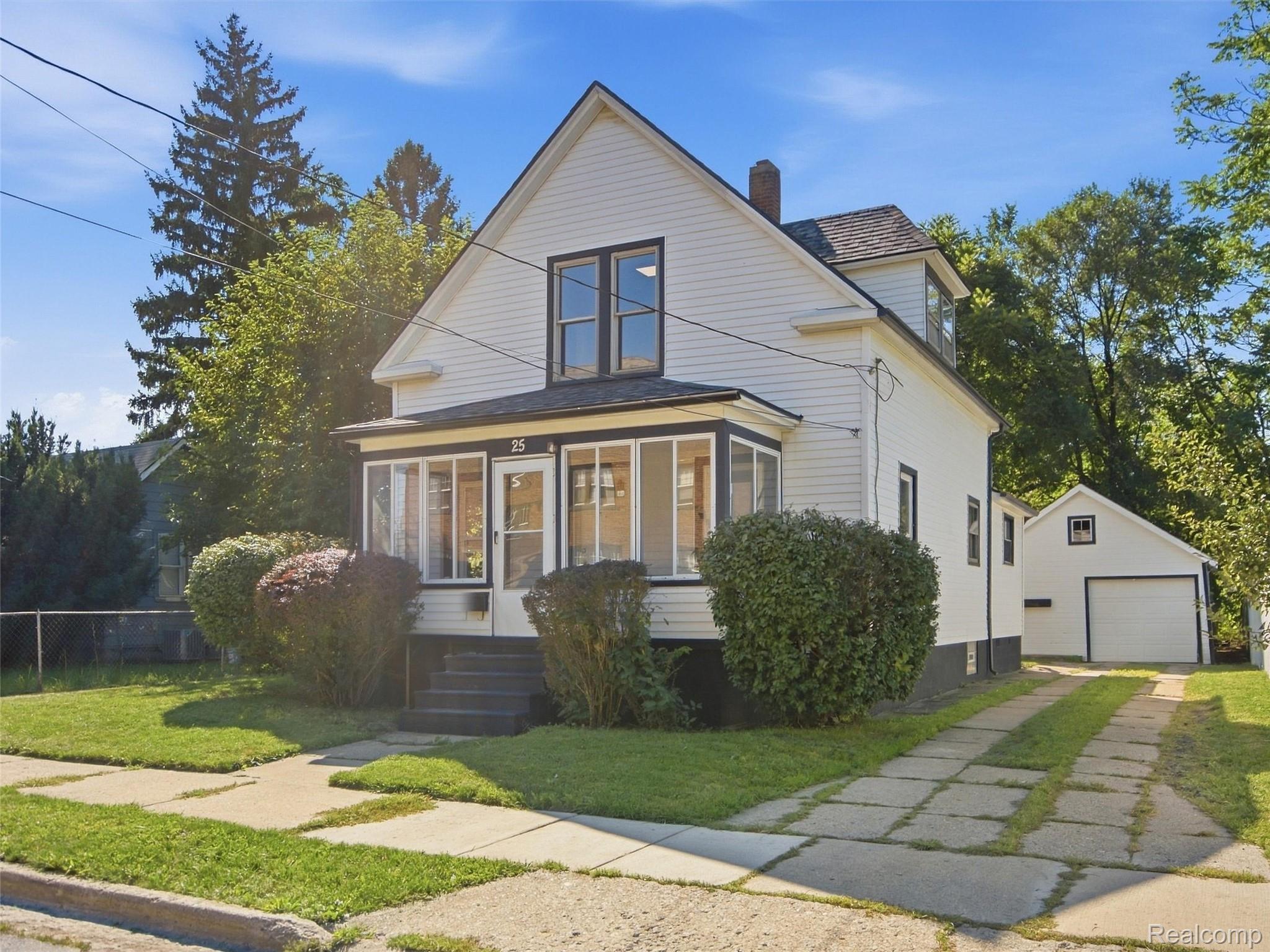 White two-story house with an enclosed porch and detached garage.