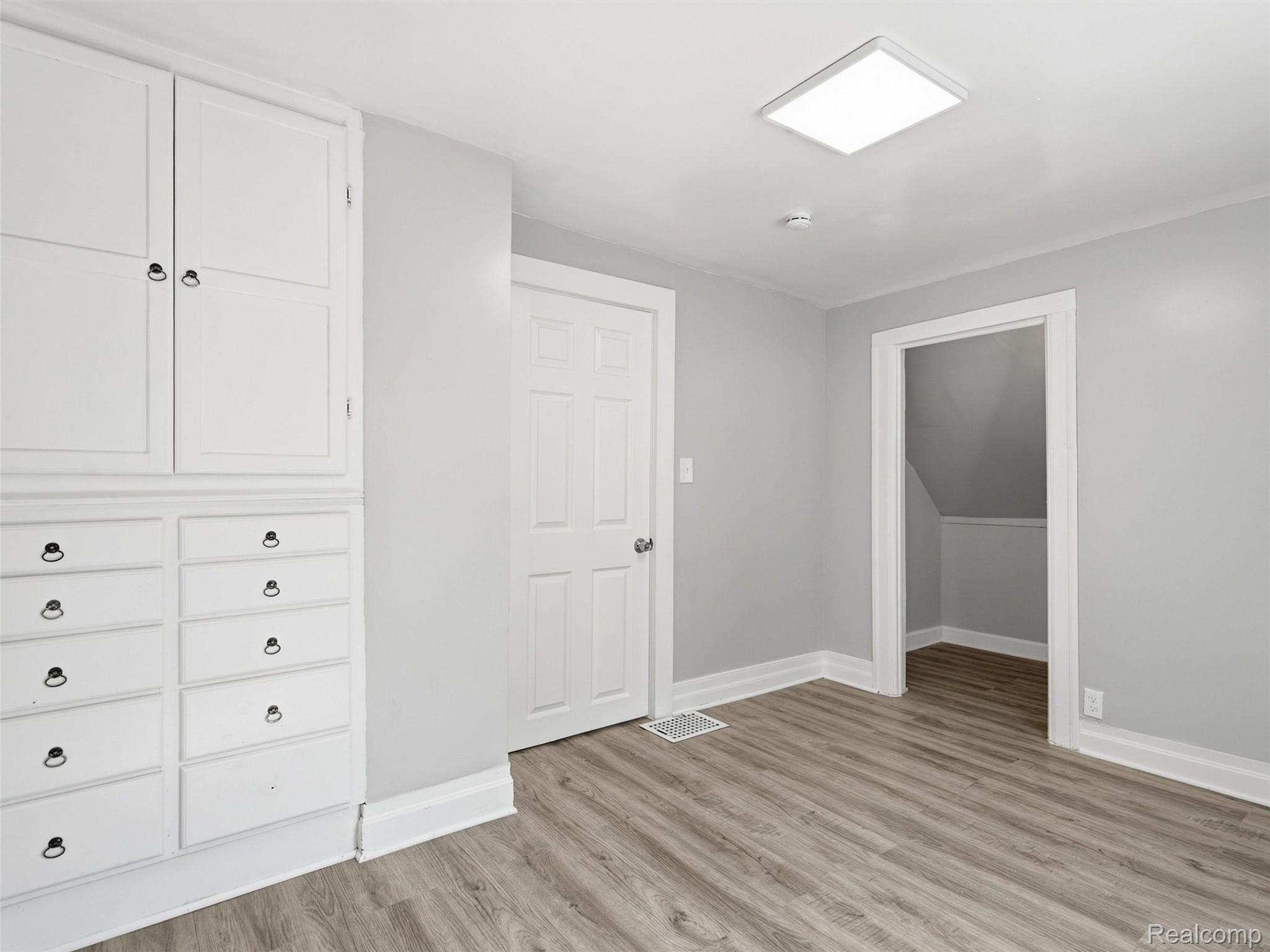 Vacant room with built-in white cabinetry and wood-look flooring.
