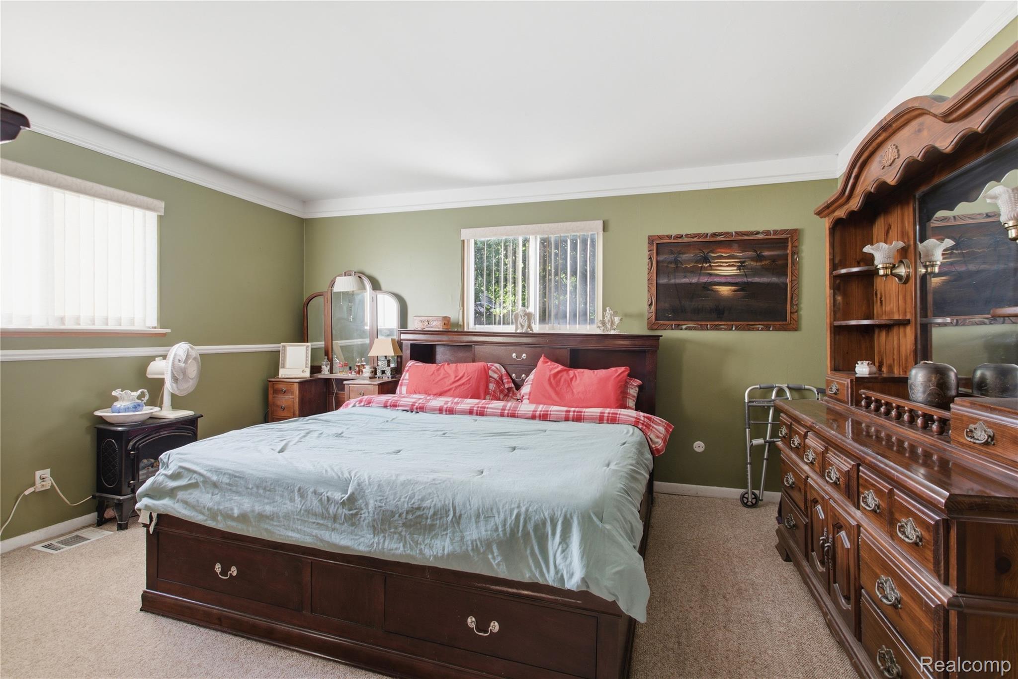 Bedroom with a dark wood sleigh bed, pale blue bedding, and ornate matching dresser and mirror.