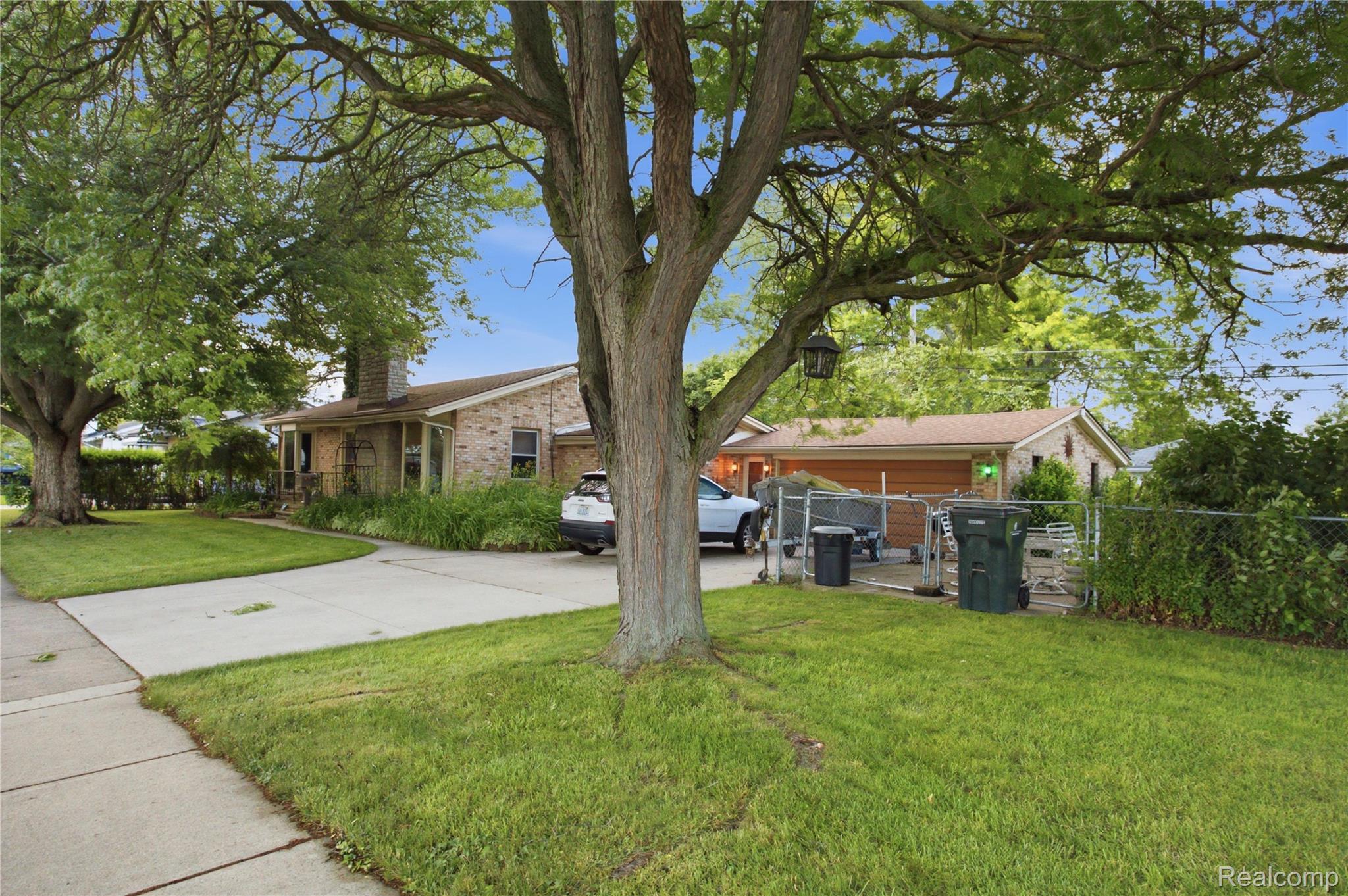 Brick ranch house with an attached garage, framed by a large shade tree and front lawn.