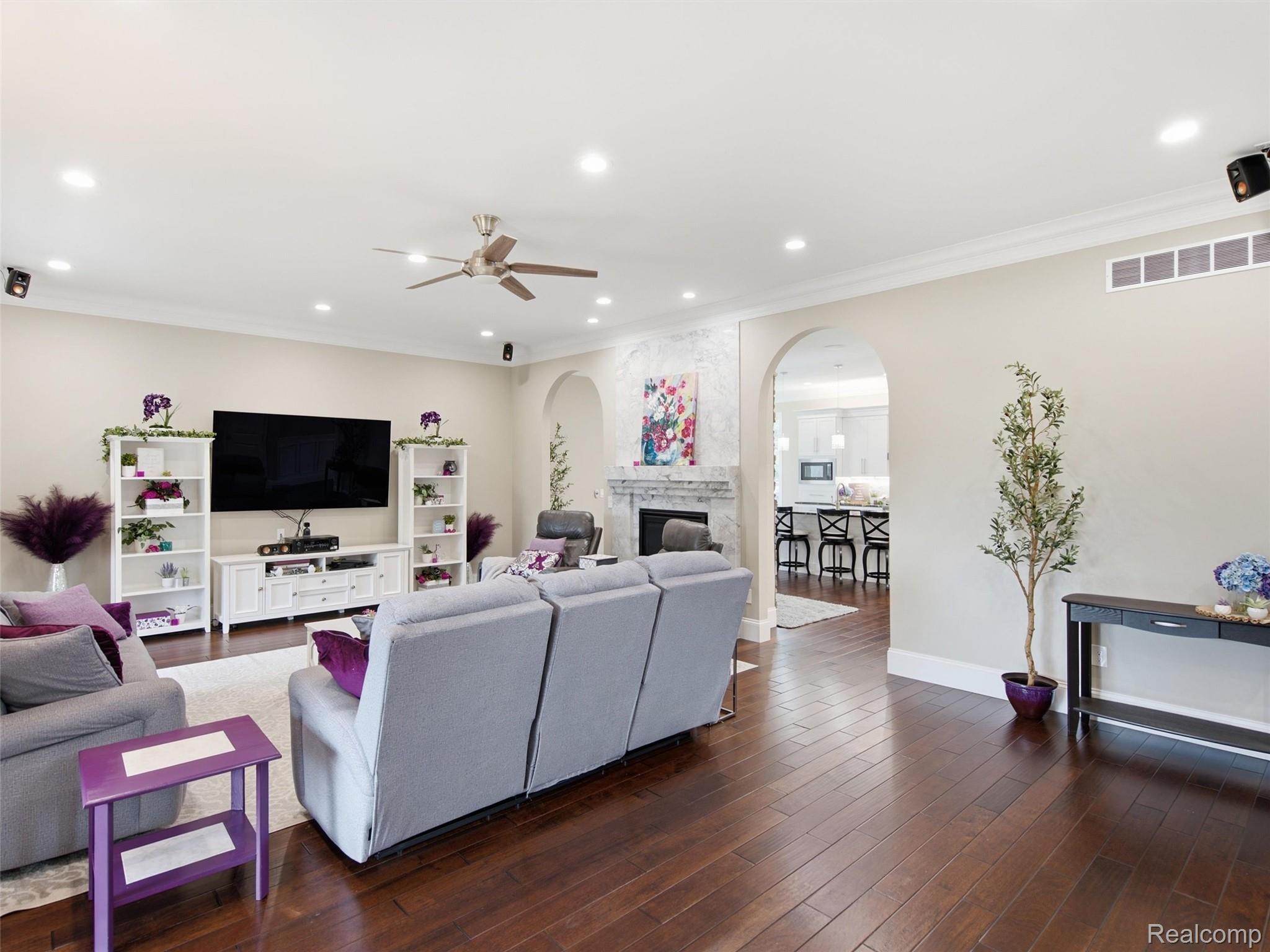 Living room with gray sofas, marble fireplace, and arched opening to the kitchen.