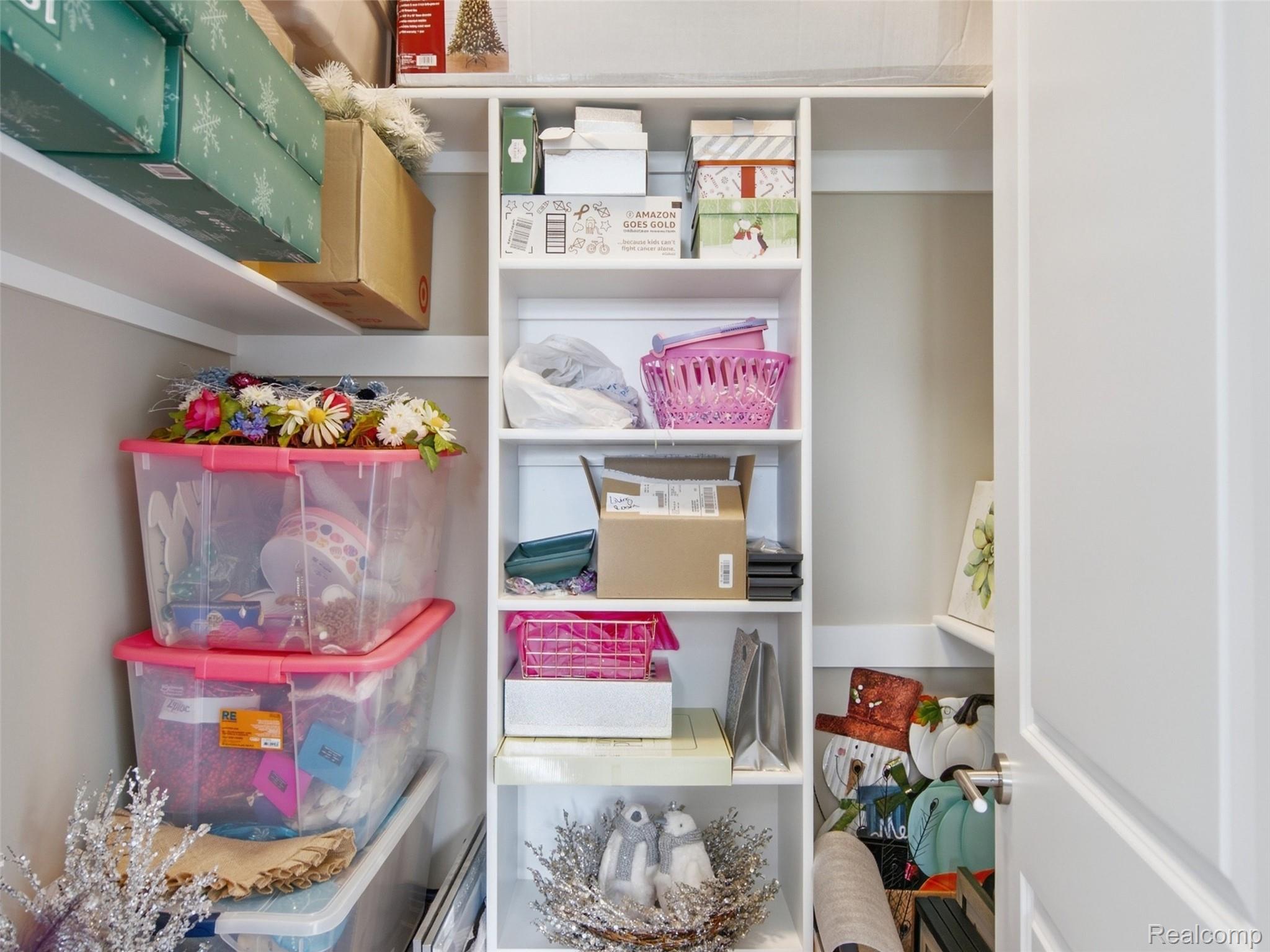 Storage closet with built-in shelves packed with bins, boxes, baskets, and seasonal decorations.