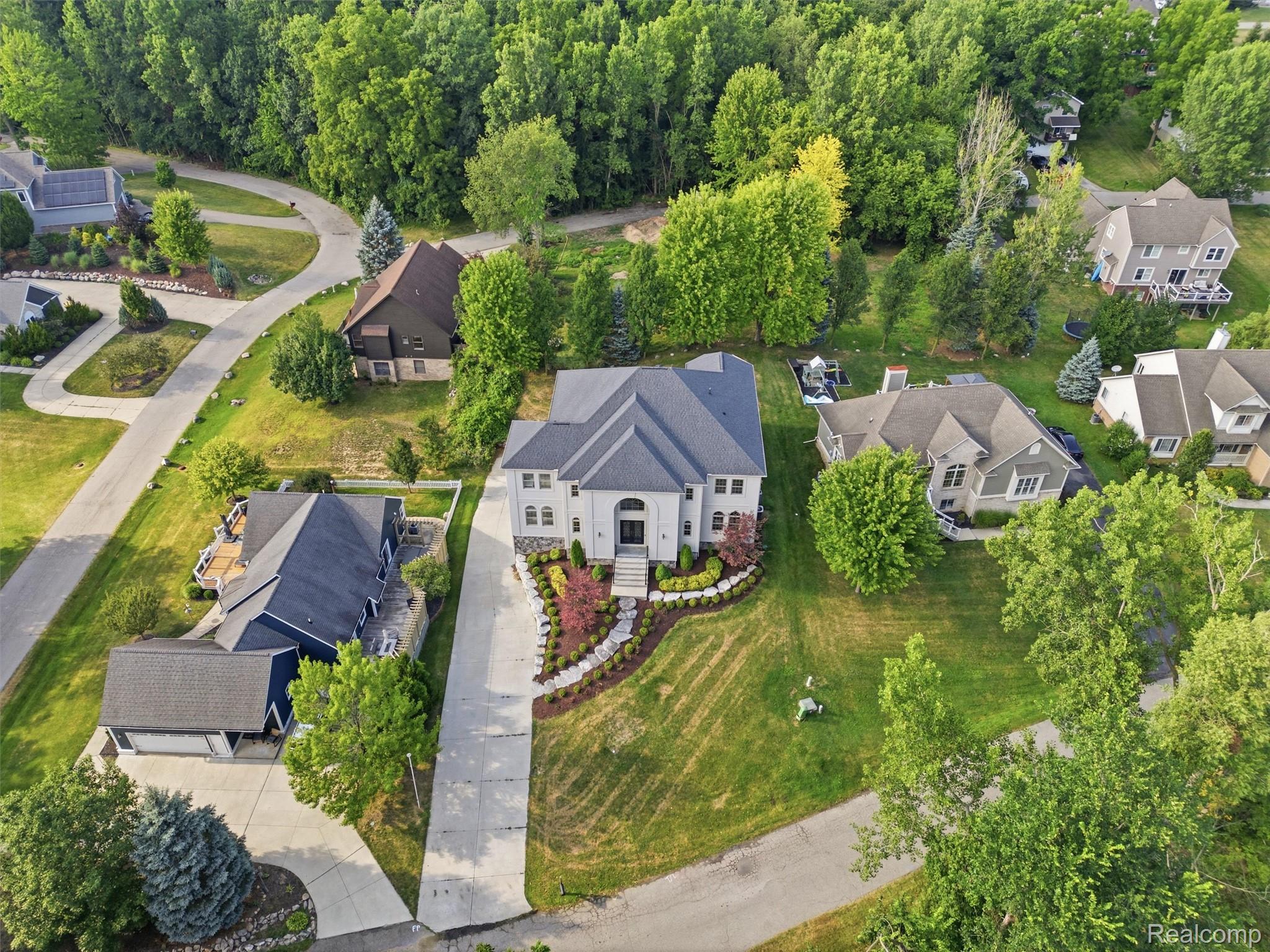 Aerial view of a two-story home with a landscaped front yard and long driveway.
