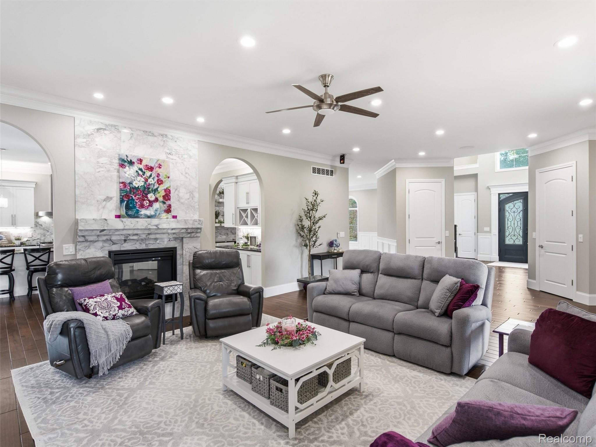 Furnished living room with a marble-look fireplace, gray sofas, and an open view to the entryway.