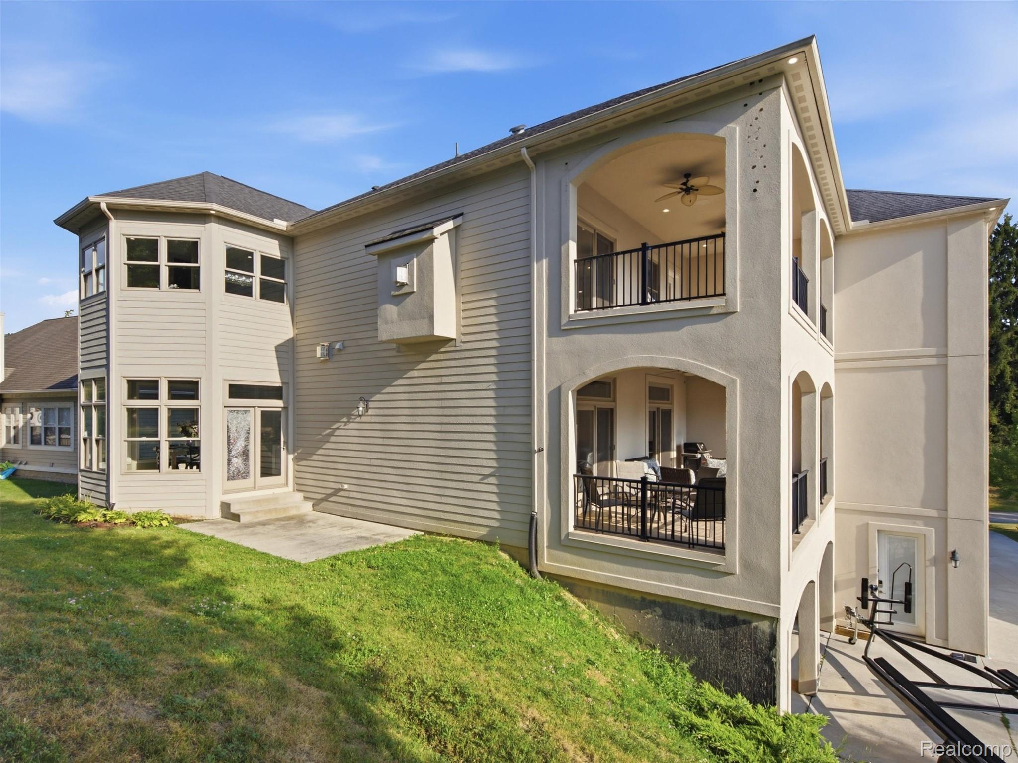Rear of a two-story gray-sided home with two covered balconies and outdoor seating.