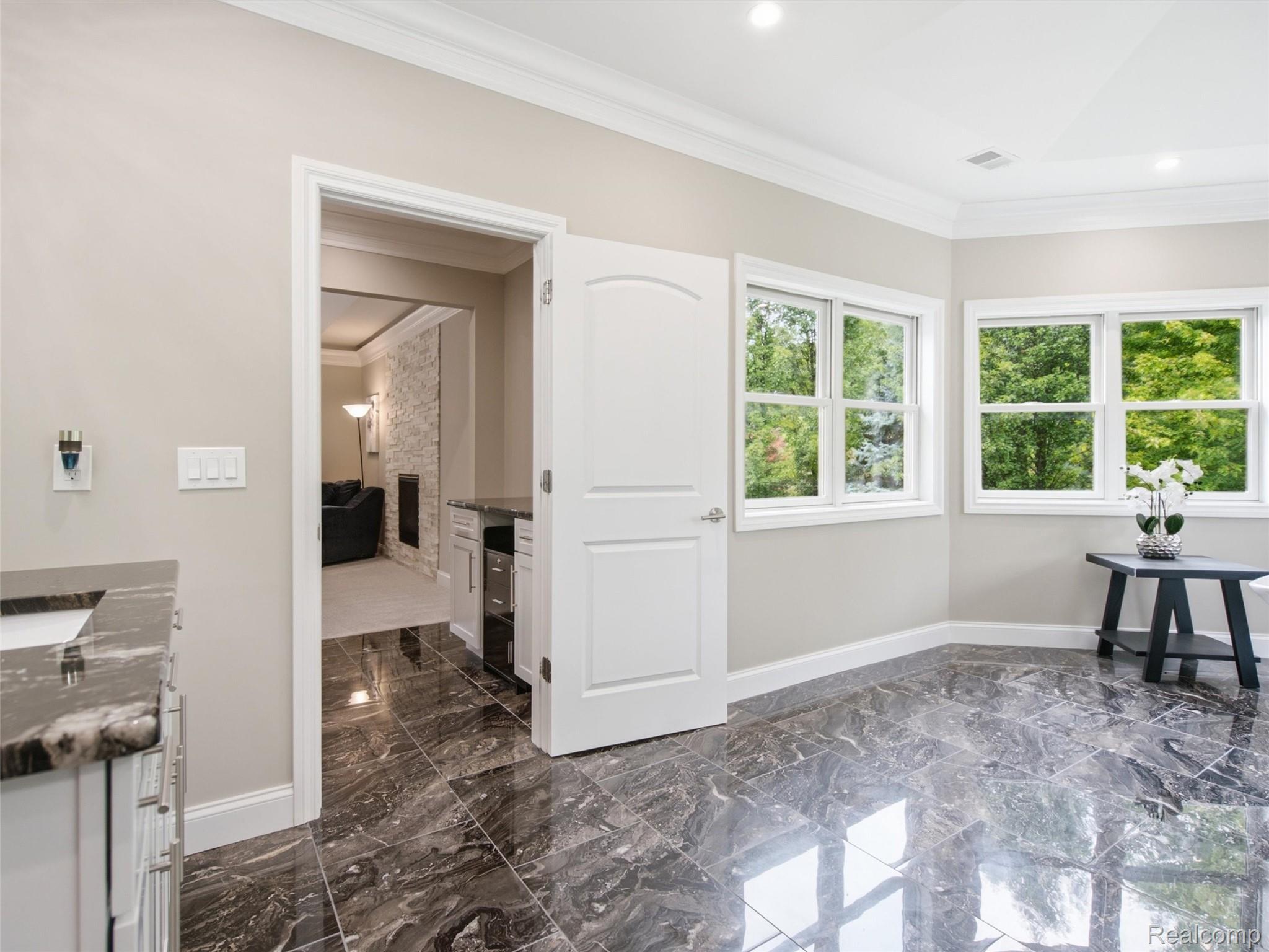 Kitchen with glossy dark tile floors, large windows, and an open doorway to the living room.
