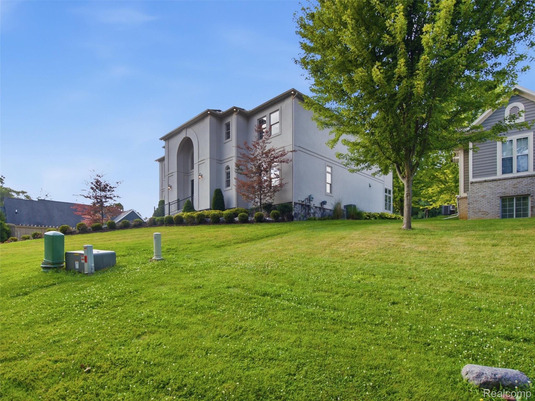 Two-story gray house with a tall arched entry above a broad sloping lawn.