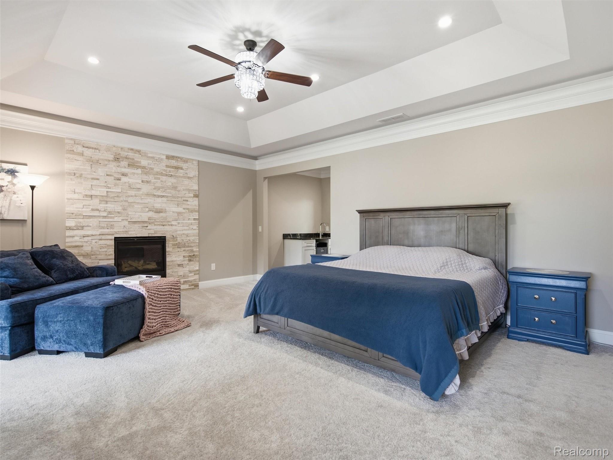 Furnished bedroom with a blue sofa and stone fireplace wall beside the bed.