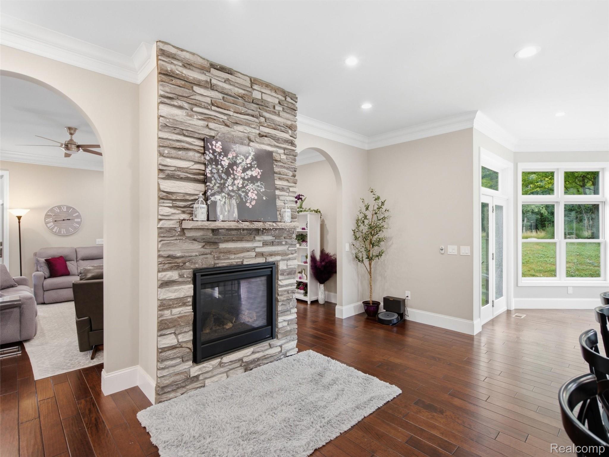 Living room with a floor-to-ceiling stone fireplace, dark hardwood floors, and large windows.