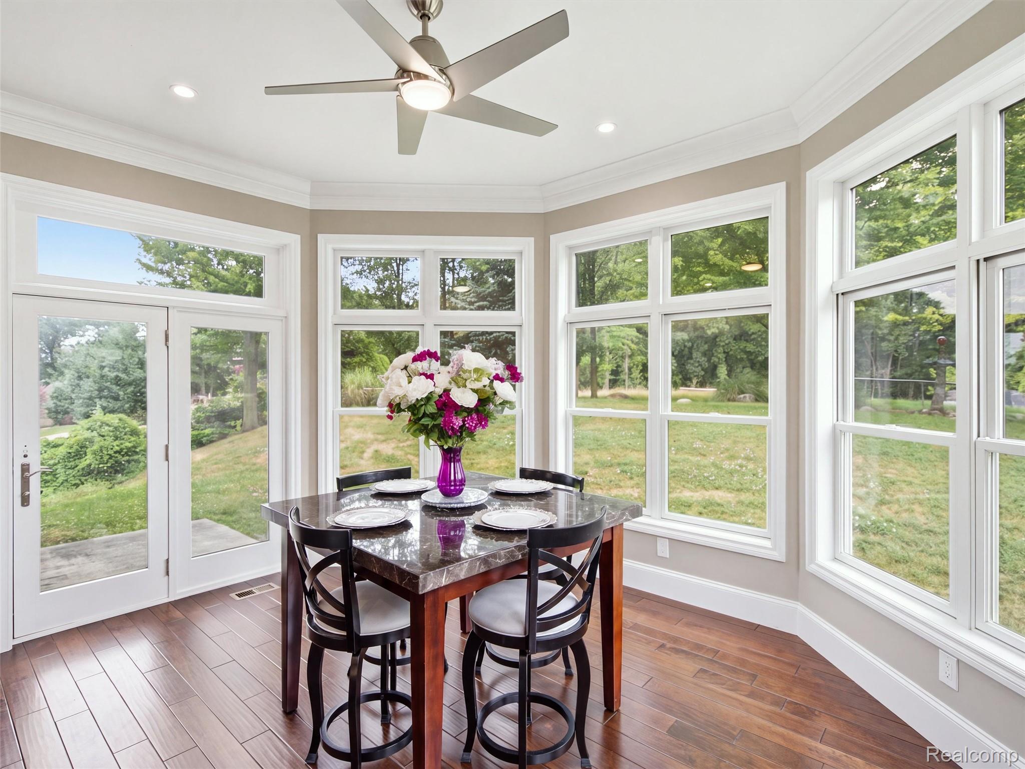 Dining area with a set table and large windows overlooking a green yard.