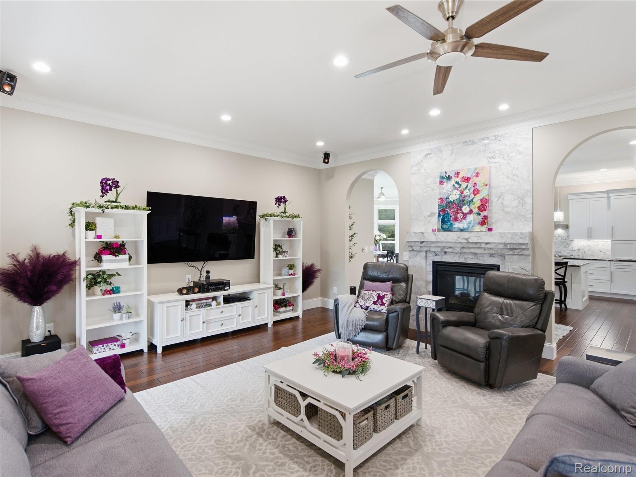 Living room with a marble fireplace, wall-mounted television, and gray seating.