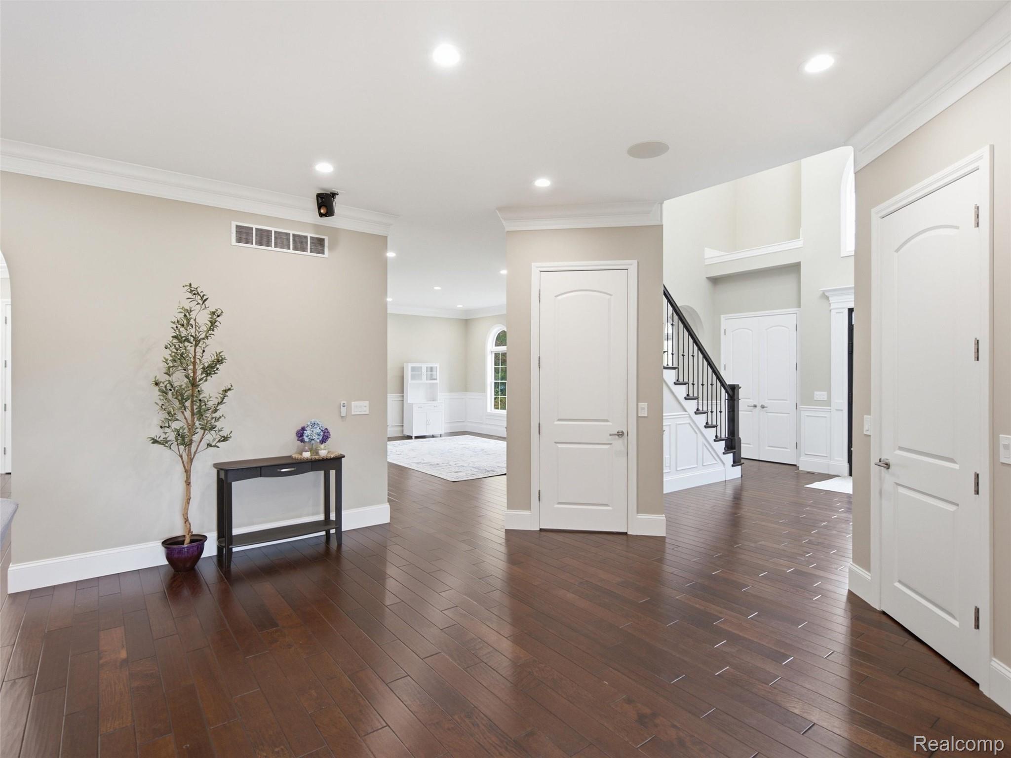 Entryway with dark hardwood floors, a console table, and a staircase with black railing.