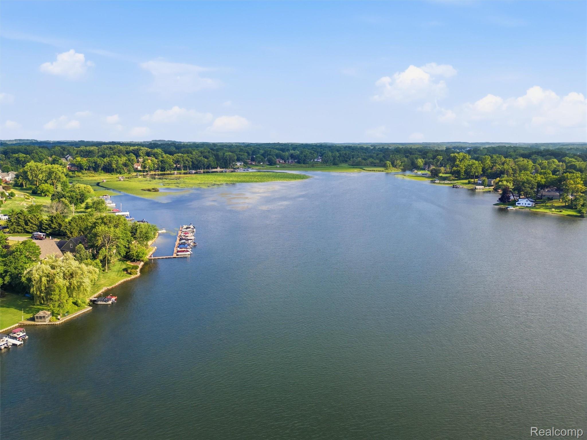 Aerial view of a lake with wooded shorelines, waterfront homes, docks, and boats.