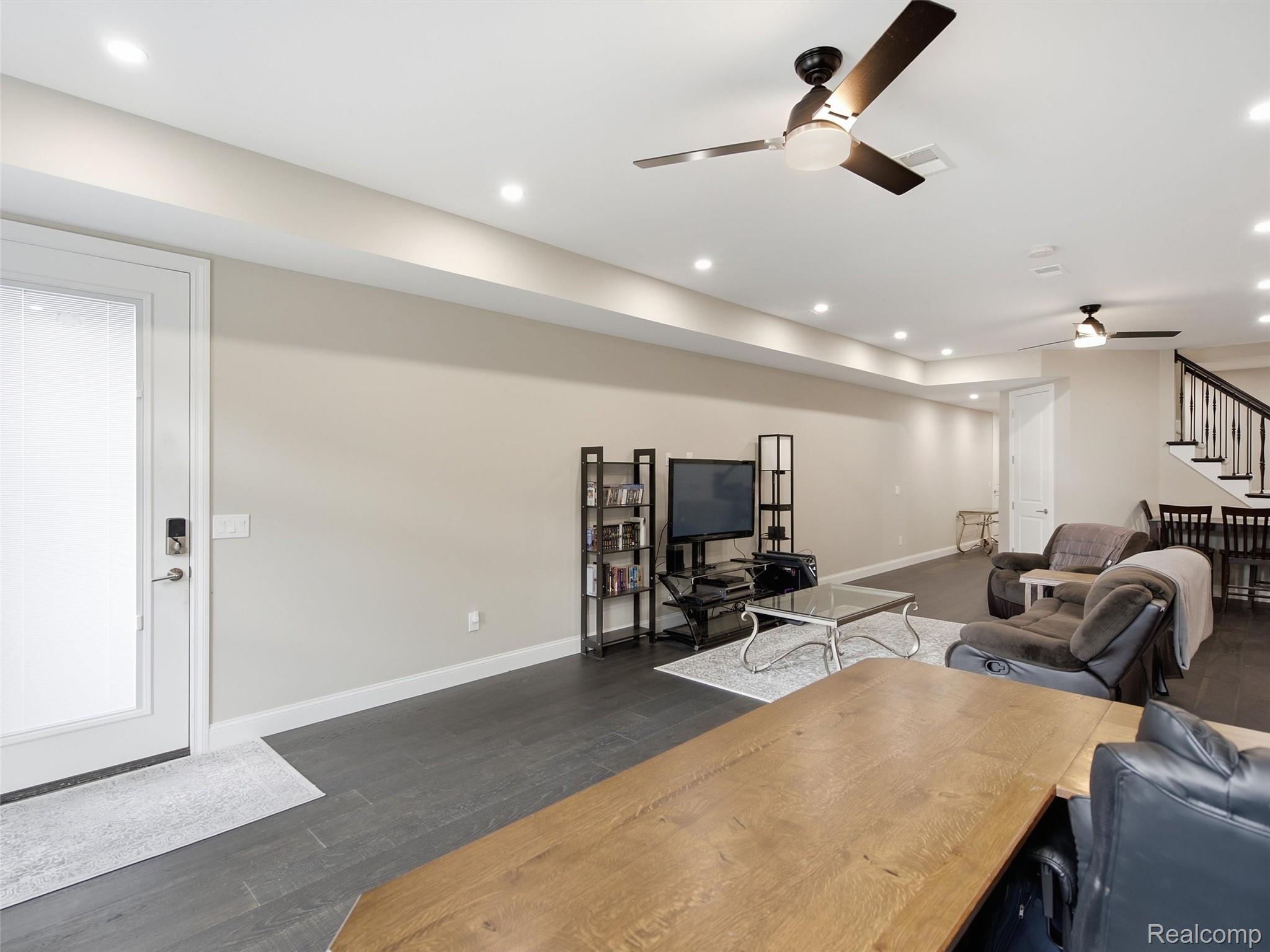 Living room with gray recliners, a media center, and stairs beside an adjoining dining area.