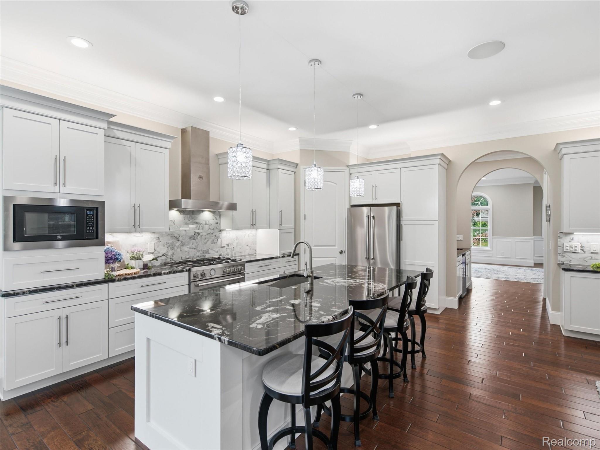 Kitchen with white cabinets, a black marble island, and stainless steel appliances.