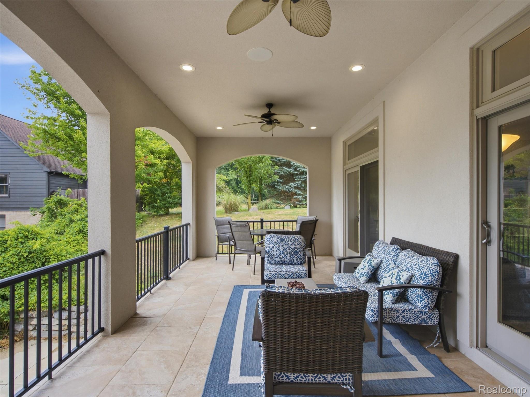 Covered patio with arched openings, blue-and-white seating, and views of a leafy garden.