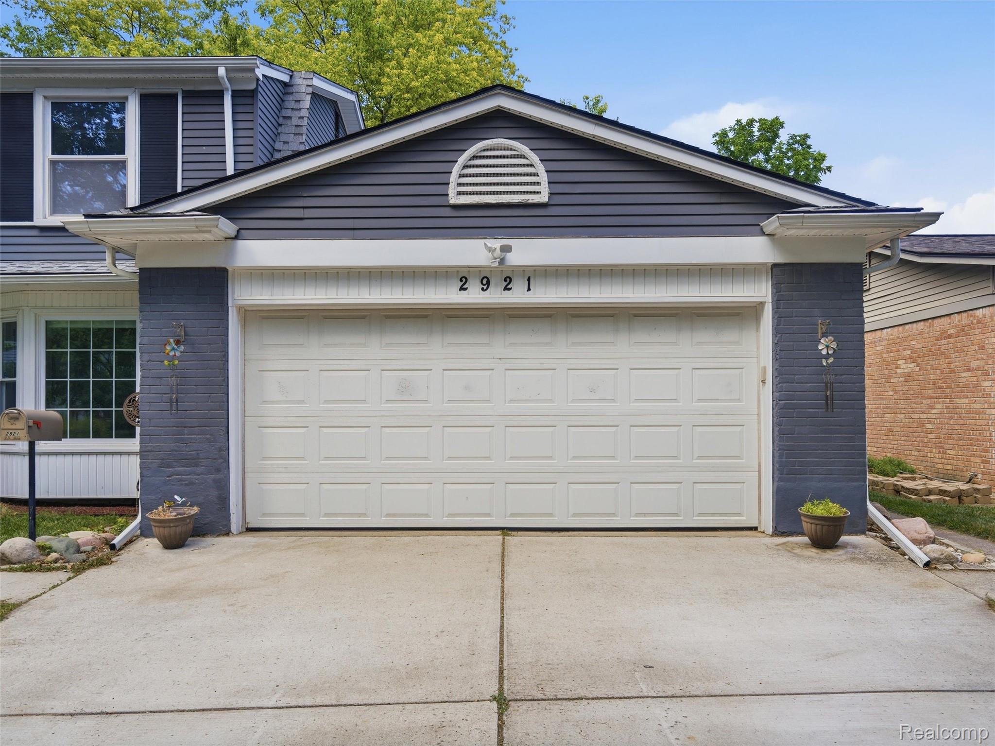 House exterior with a white double garage door, dark blue-gray siding, and number 2921.