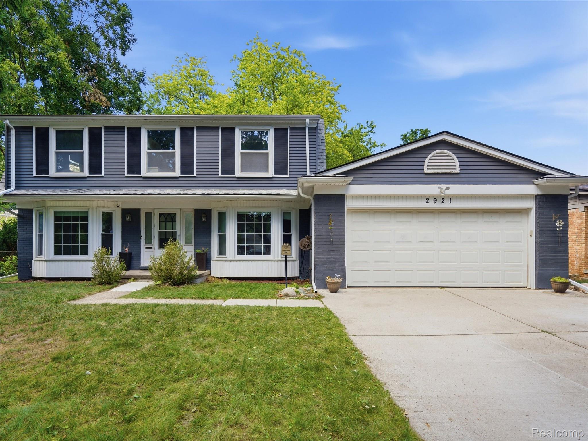 Two-story gray house with white trim, a covered entry, and an attached two-car garage.