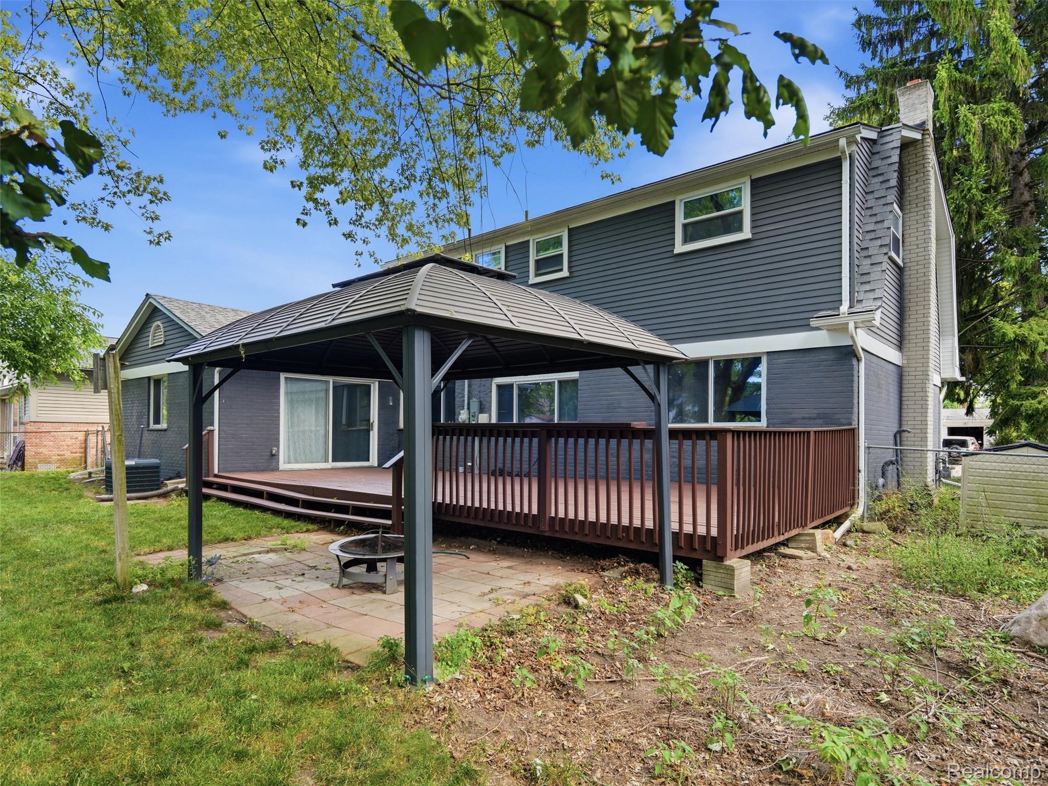 Rear of a gray two-story house with a raised deck and covered patio pavilion.