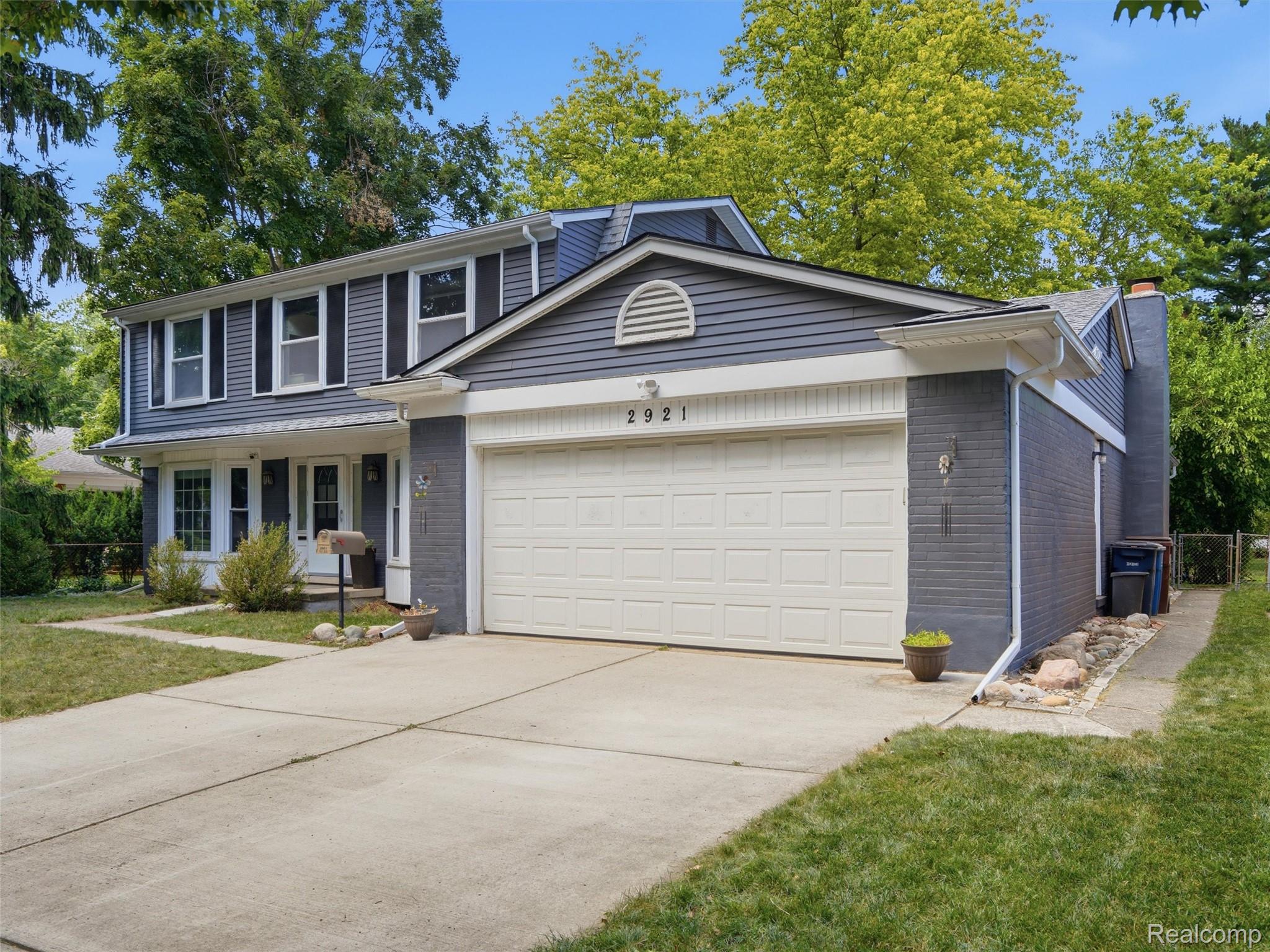 Two-story gray house with a white double garage and broad concrete driveway.