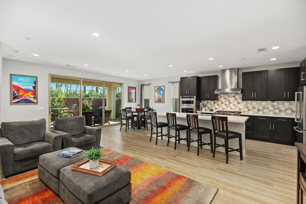 Open-plan living room and kitchen with dark cabinetry, island seating, and sliding glass doors.