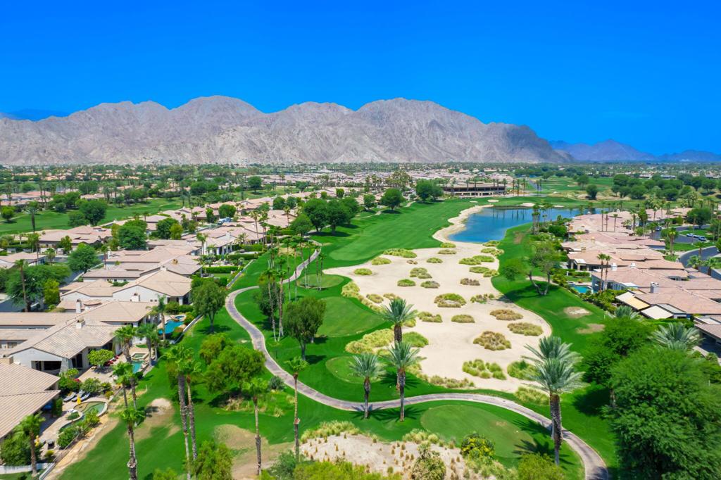 Aerial view of a La Quinta golf course community with a lake and desert mountains.