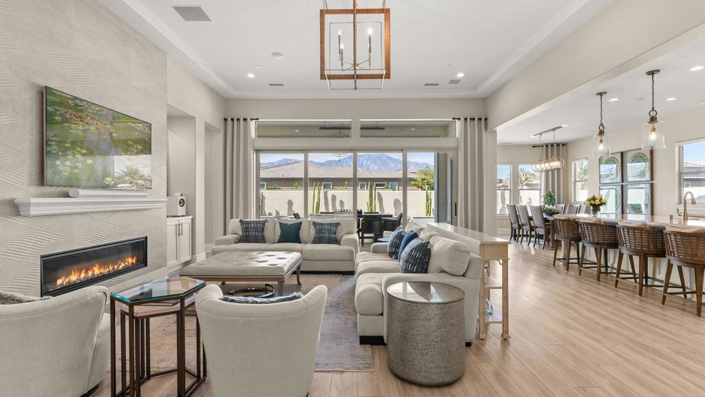 Open-plan living room with a linear fireplace, dining area, and mountain views through glass doors.