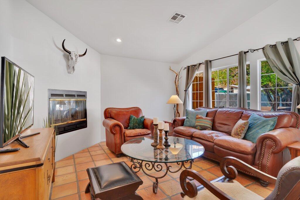 Living room with leather sofas, terracotta tile floors, and a built-in fireplace.