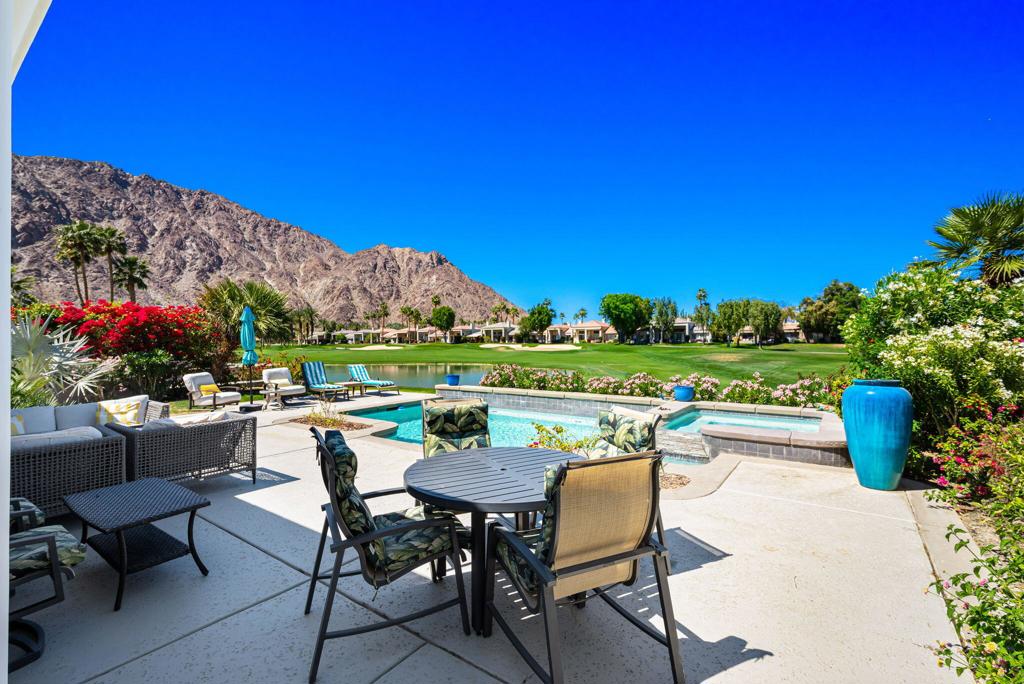Backyard pool and patio with outdoor seating, golf course, and mountains beyond.