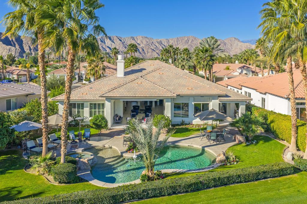 Aerial view of a home with a pool, landscaped yard, and mountain backdrop.