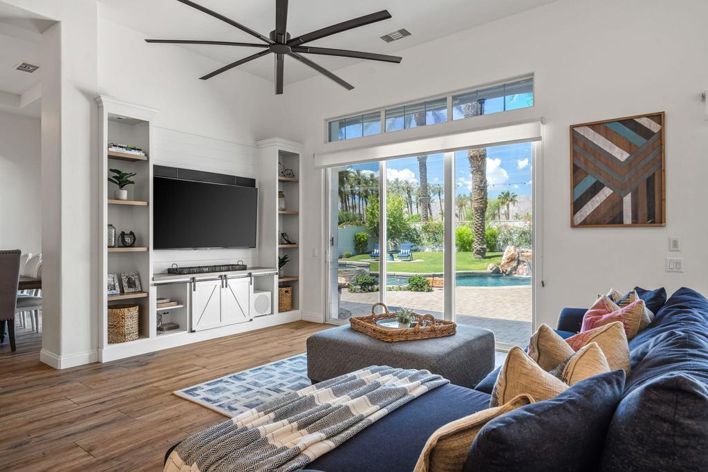 Living room with built-in entertainment center and sliding doors overlooking a pool and landscaped yard.