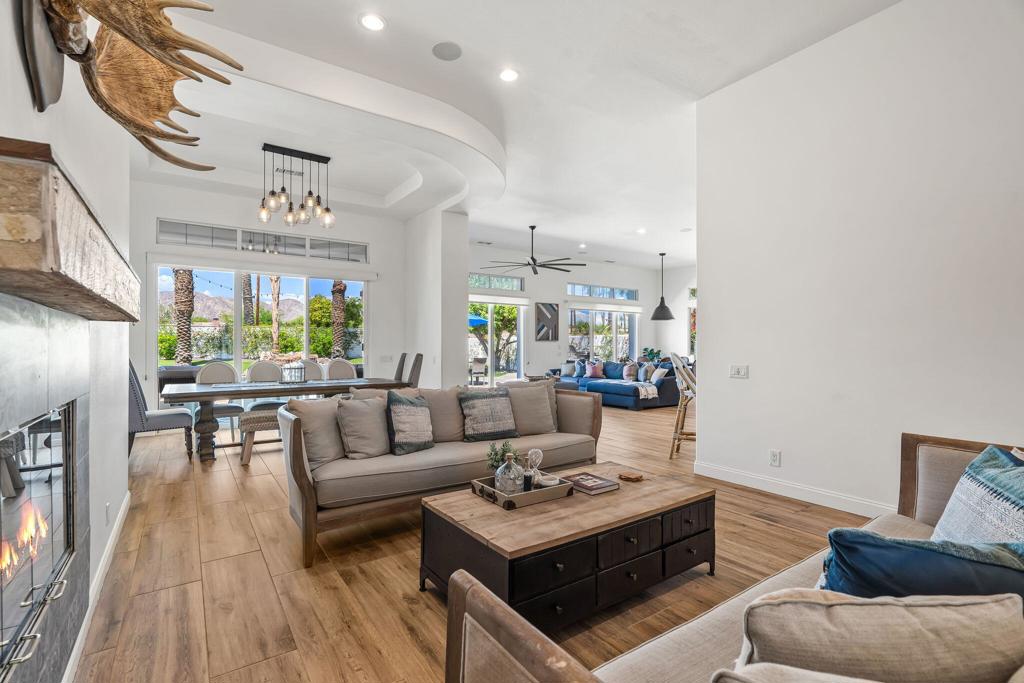 Open-plan living room with a fireplace, dining area, and mountain views through large windows.
