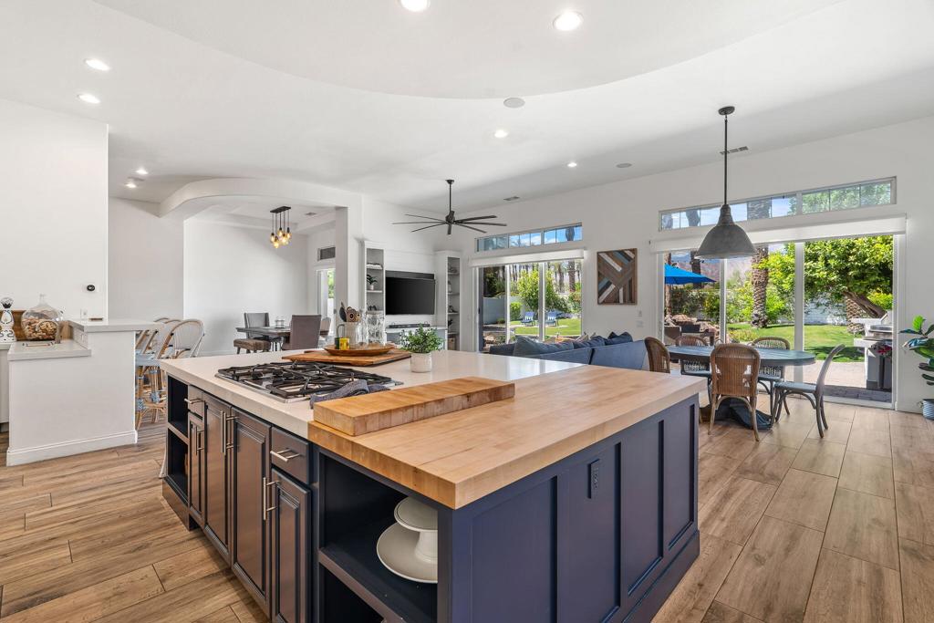 Open-plan kitchen with a navy island, butcher-block countertop, gas cooktop, and sliding doors to the garden.