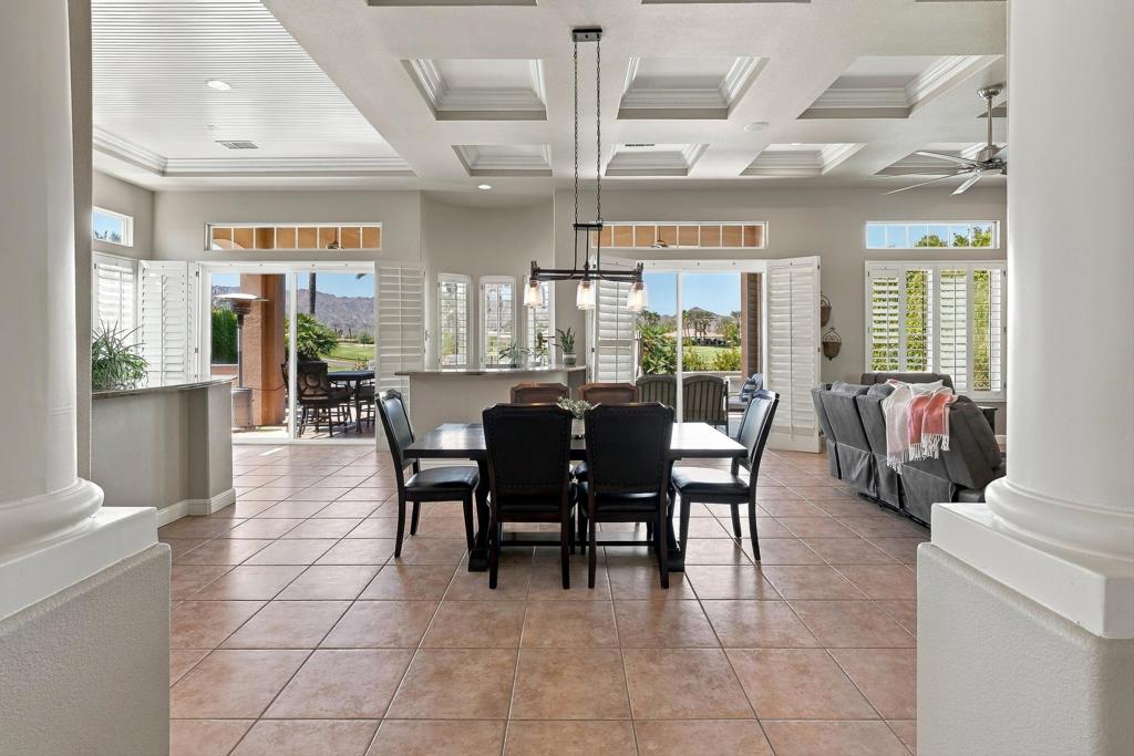 Open-plan dining and living room with a coffered ceiling and mountain views through shuttered windows.
