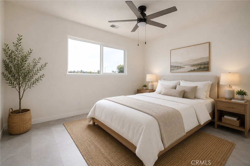 Staged bedroom with a white bed, ceiling fan, and large window.
