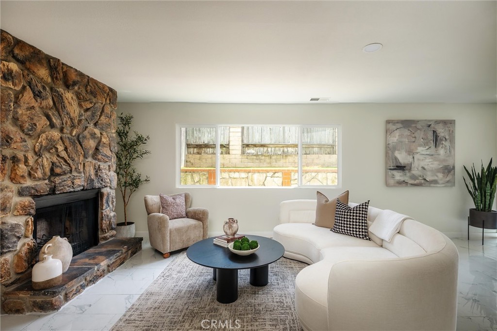 Living room with a stone fireplace, curved white sectional, and wide window.