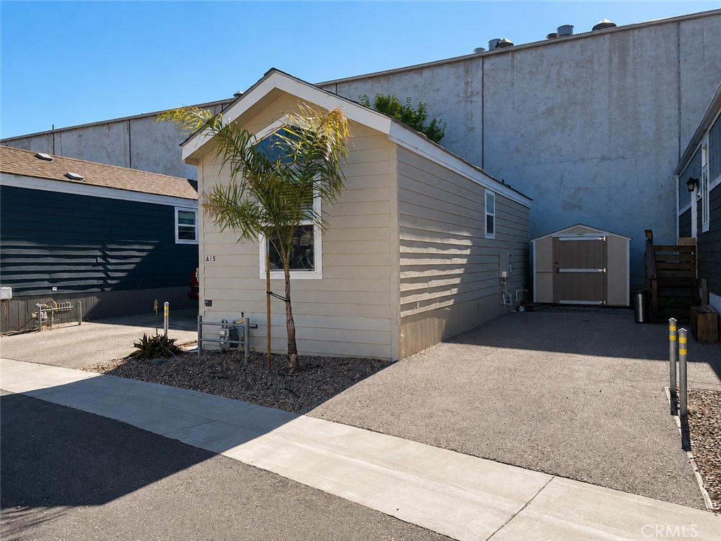 Light-colored A15 home with a palm tree in front and paved parking beside it.