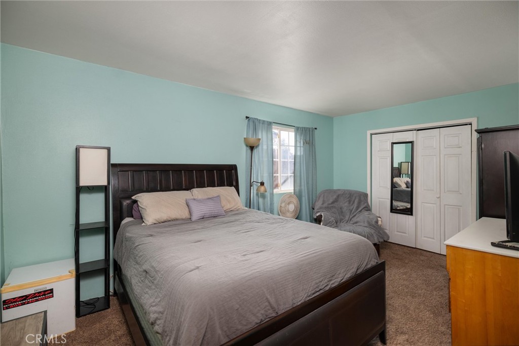 Bedroom with a large bed, turquoise walls, and mirrored closet doors.