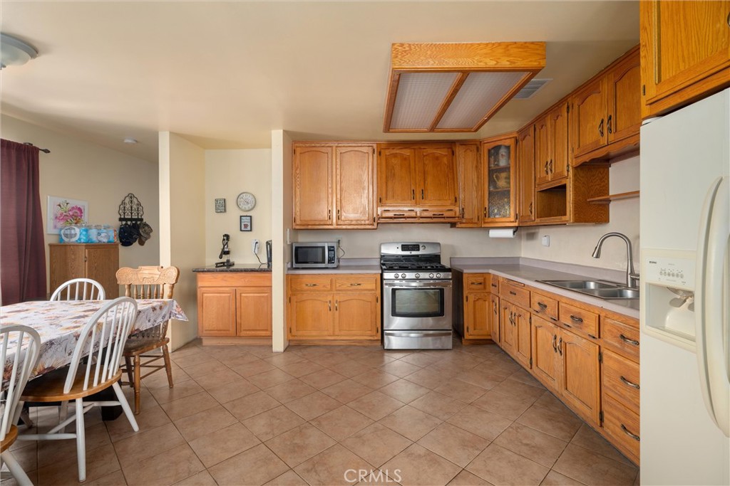 Kitchen with honey-colored wood cabinets, stainless steel appliances, and an adjoining dining area.