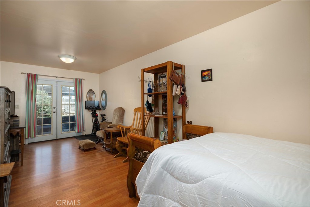 Bedroom with a white bed, wood furnishings, and glass doors opening to a patio.