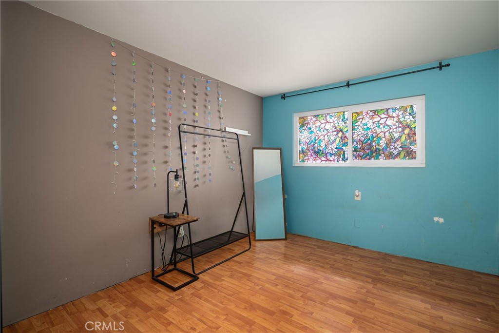 Room with turquoise and taupe walls, a colorful stained-glass window, and wood-pattern flooring.