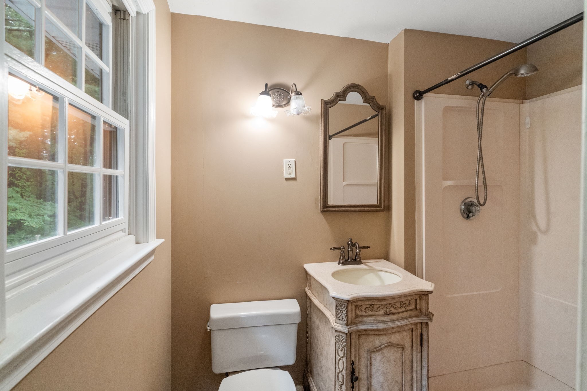 Bathroom with a carved wood vanity and large window overlooking greenery.