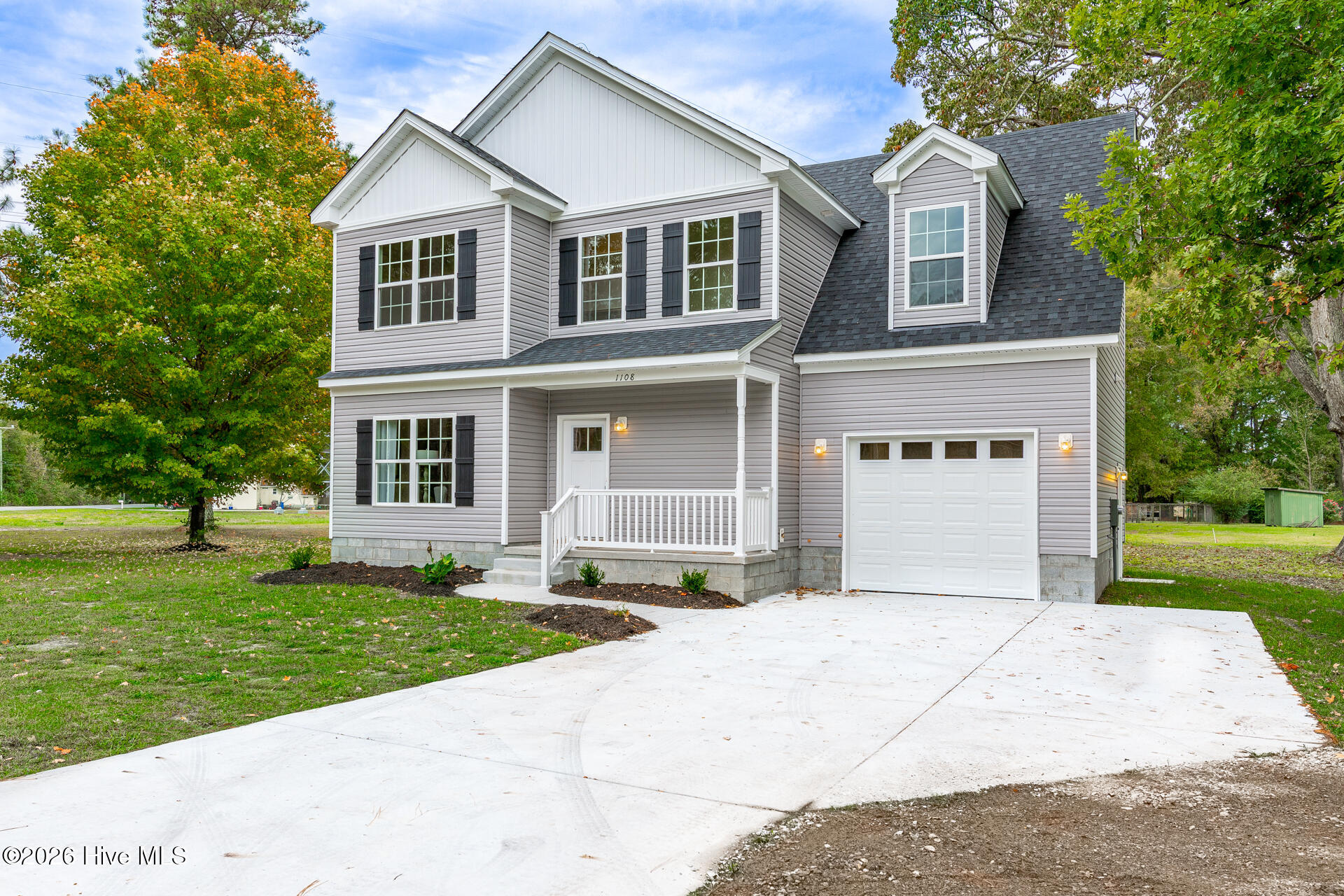 Two-story gray house with a covered porch, attached garage, and wide concrete driveway.