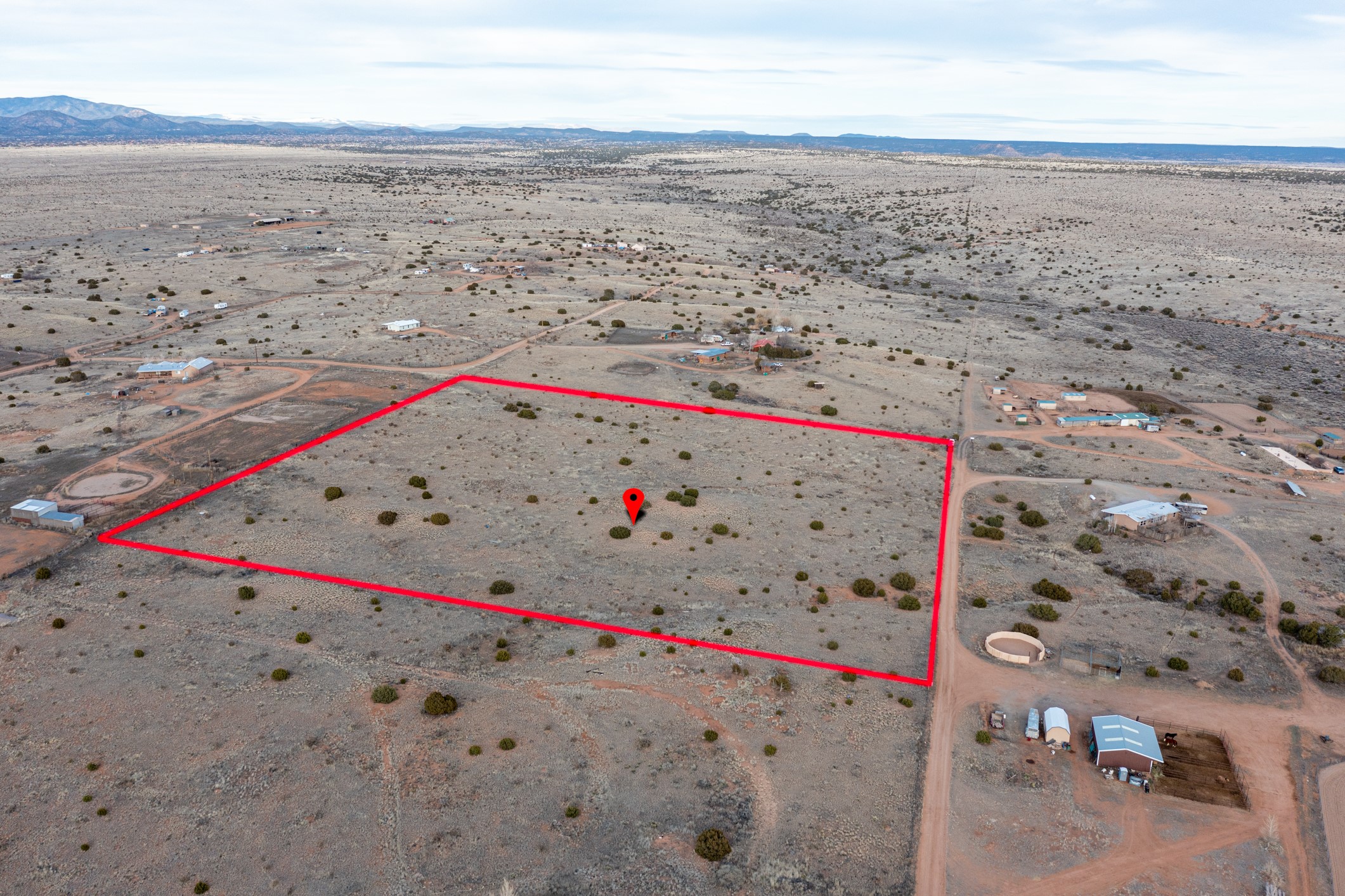 Vacant rural parcel outlined in red, with sparse scrub and distant mountains.