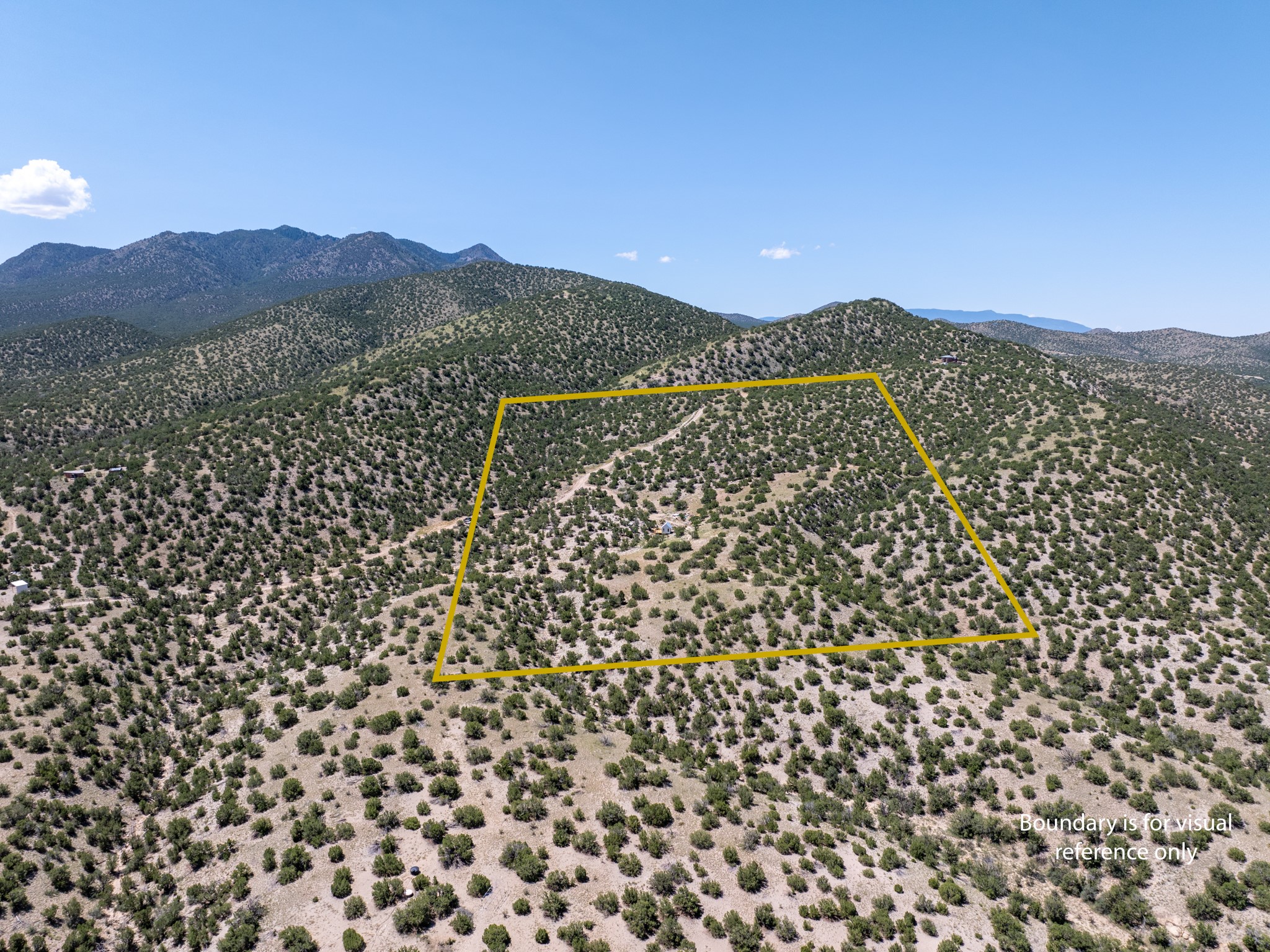 Aerial view of scrub-covered land outlined in yellow, with mountain ridges behind it.