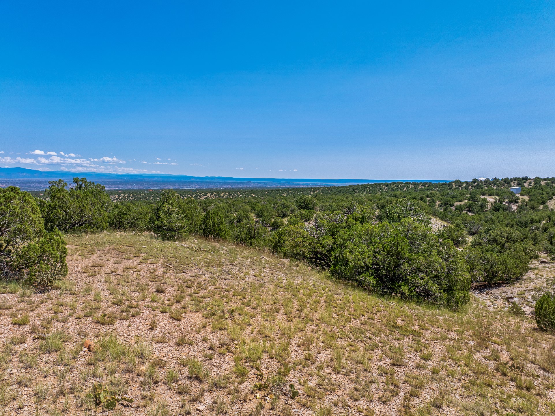 Rocky vacant land with juniper scrub and distant mountain views.